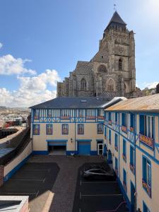 a blue and white building with a church in the background at Hôtel De Calais in Le Tréport