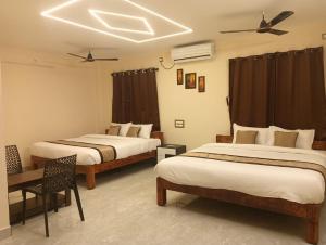 a hotel room with two beds and a ceiling at Auro Green Villa in Pondicherry +18 photos