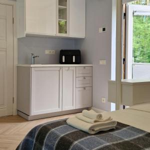 a kitchen with white cabinets and towels on a rug at Poilsio nameliai TekaTeka in Anykščiai