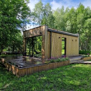 a wooden house in the grass with a deck at Poilsio nameliai TekaTeka in Anykščiai