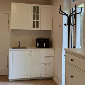 a kitchen with white cabinets and a black microwave at Poilsio nameliai TekaTeka in Anykščiai +10 photos