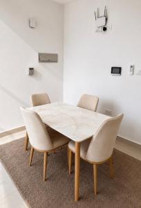 a dining room table with chairs and a white wall at Cozy Apartment in Boshar in Muscat