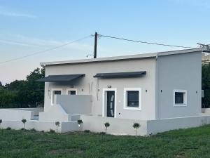 a white house with palm trees in front of it at Villa Ziglos by Karda Suites in Chios