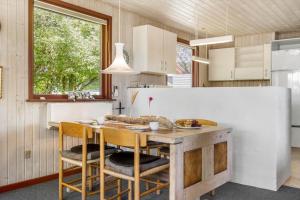 a kitchen with a table and chairs and a refrigerator at 2218-Ringkobing-Milevej-22 in Klegod