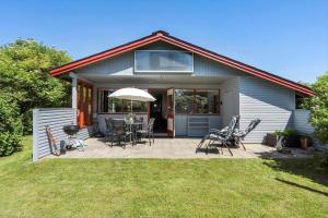 a house with a patio with chairs and an umbrella at 2218-Ringkobing-Milevej-22 in Klegod