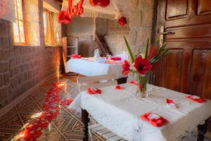 a room with two tables with red flowers on it at Tsarasoa Lodge in Ambalavao