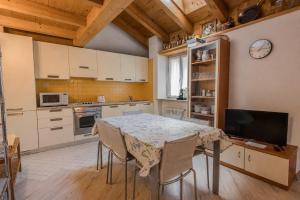 a kitchen with a table with chairs and a tv at Casa Caorer by Sunhome Fiemme in Predazzo +5 photos
