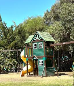 a playground with a small house and a slide at Cabañas La Campiña Algarrobo in Algarrobo