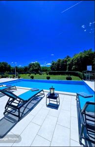 a large swimming pool with two chairs and a table at Villa Heaven Green in Pazin