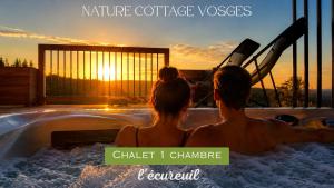 a couple sitting in a hot tub watching the sunset at Nature Cottage Vosges in Anould