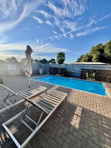 a swimming pool with two lounge chairs next to a swimming pool at Lighthouse Guesthouse & Cafe in Groblersdal