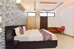 a bedroom with a bed and a red chair at FabHotel Moon Stone, Near Jawahar Circle - World Trade Park in Jaipur