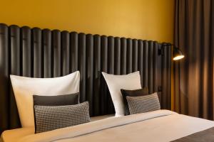 a bed with four pillows in front of a radiator at Hôtel Diana Dauphine in Strasbourg