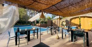 a patio with tables and chairs and a swimming pool at Mas la Provence in L'Isle-sur-la-Sorgue