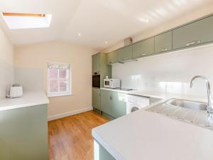 a kitchen with white counters and green cabinets at The Old Bakery - Uk48319 in Berwick-Upon-Tweed +17 photos