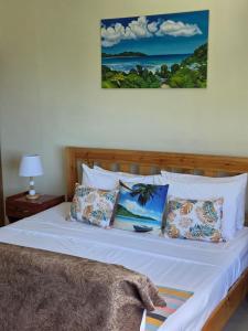 a bed with white sheets and pillows on it at Sunset View Self Catering in Anse Boileau