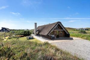 a small house with a thatched roof in a field at 299-Ringkobing-Havklitvej-24 in Klegod