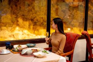 Eine Frau sitzt mit einem Glas Wein an einem Tisch. in der Unterkunft Unzen Kyushu Hotel in Unzen