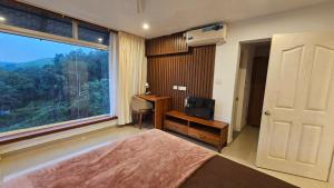 a bedroom with a bed and a desk and a window at Celestial Nymph by Natureloom in Vagamon