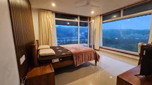 a bedroom with a bed and a large window at Celestial Nymph by Natureloom in Vagamon