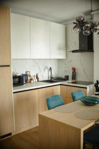a kitchen with white cabinets and a table with blue chairs at RIVER VIEW & Private Parking - Baia Mare in Baia Mare