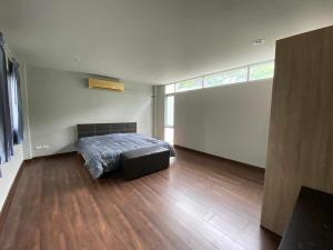 a bedroom with a bed in a room with wooden floors at Home Sukhumvit 49 Soi 14 in Bangkok