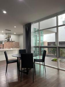 a dining room with a table and chairs and a large window at Home Sukhumvit 49 Soi 14 in Bangkok