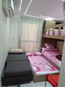 two beds in a small room with pink sheets at شاليه غرفتين ببورتوسعيد للعائلات فقط in Port Said