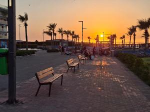a row of benches on a sidewalk at sunset at شاليه غرفتين ببورتوسعيد للعائلات فقط in Port Said