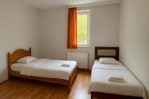 two beds in a small room with a window at METRO Hotel in Gusinje