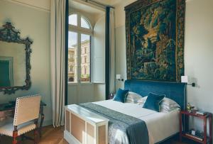 a bedroom with a large painting above a bed at Rocco Forte Hotel Savoy in Florence +97 photos