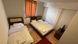 two beds in a small room with a window at METRO Hotel in Gusinje +7 photos