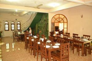 a woman standing in a restaurant with tables and chairs at Nandawanam Guest House Pasikuda in Kalkudah