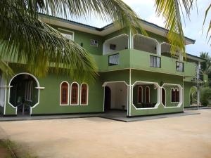 a green house with a palm tree in front of it at Nandawanam Guest House Pasikuda in Kalkudah
