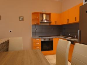 a kitchen with orange cabinets and a wooden table at Nature sunset apartment in Ubli