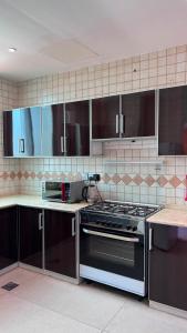 a kitchen with a stove and brown cabinets at فيلا درة العروس 2 in Durat Alarous
