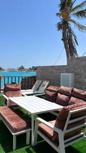 a picnic table and chairs with a palm tree in the background at فيلا درة العروس 2 in Durat Alarous