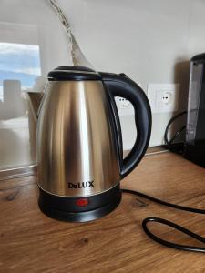 a silver and black tea kettle on a wooden table at Lakefront House in Pogradec