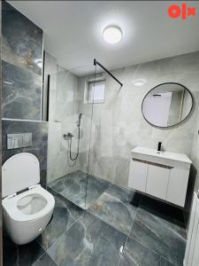 a bathroom with a toilet and a shower and a mirror at Stan na dan Tuzla in Tuzla