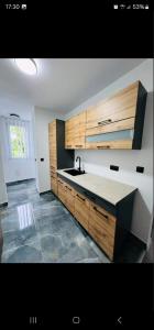 a kitchen with wooden cabinets and a sink at Stan na dan Tuzla in Tuzla