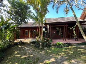 a house with palm trees in front of it at Villa Tegal Tis Ubud in Payangan