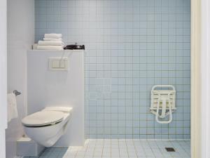 a bathroom with a toilet and a blue tile wall at Aparthotel Adagio Access Paris Bastille in Paris