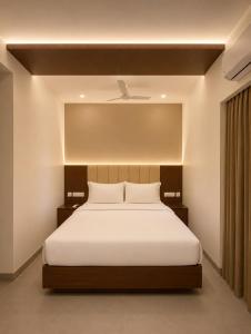 a bedroom with a large white bed with a ceiling at Arthana Grand Inn in Udumalaippettai +8 photos