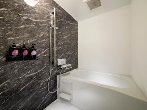 a bathroom with a shower with four bottles on the wall at Minn Sapporo Odori W14 in Sapporo +18 photos