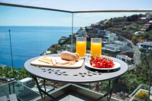 a table with a plate of food and two glasses of orange juice at Pérola de São João in Calheta