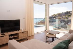 a living room with a television and a large window at Pérola de São João in Calheta