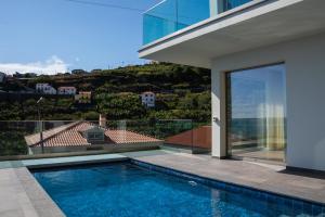 a swimming pool in front of a house at Pérola de São João in Calheta