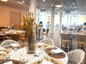 a restaurant with tables and chairs and a vase of flowers at DOMITYS - L'Alezane in Saint Lo
