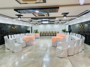 a room with rows of chairs and tables with orange accents at Hotel President, Pure Veg in Indore