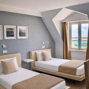 zwei Betten in einem Zimmer mit Fenster in der Unterkunft Hotel Nobu Peniche in Peniche